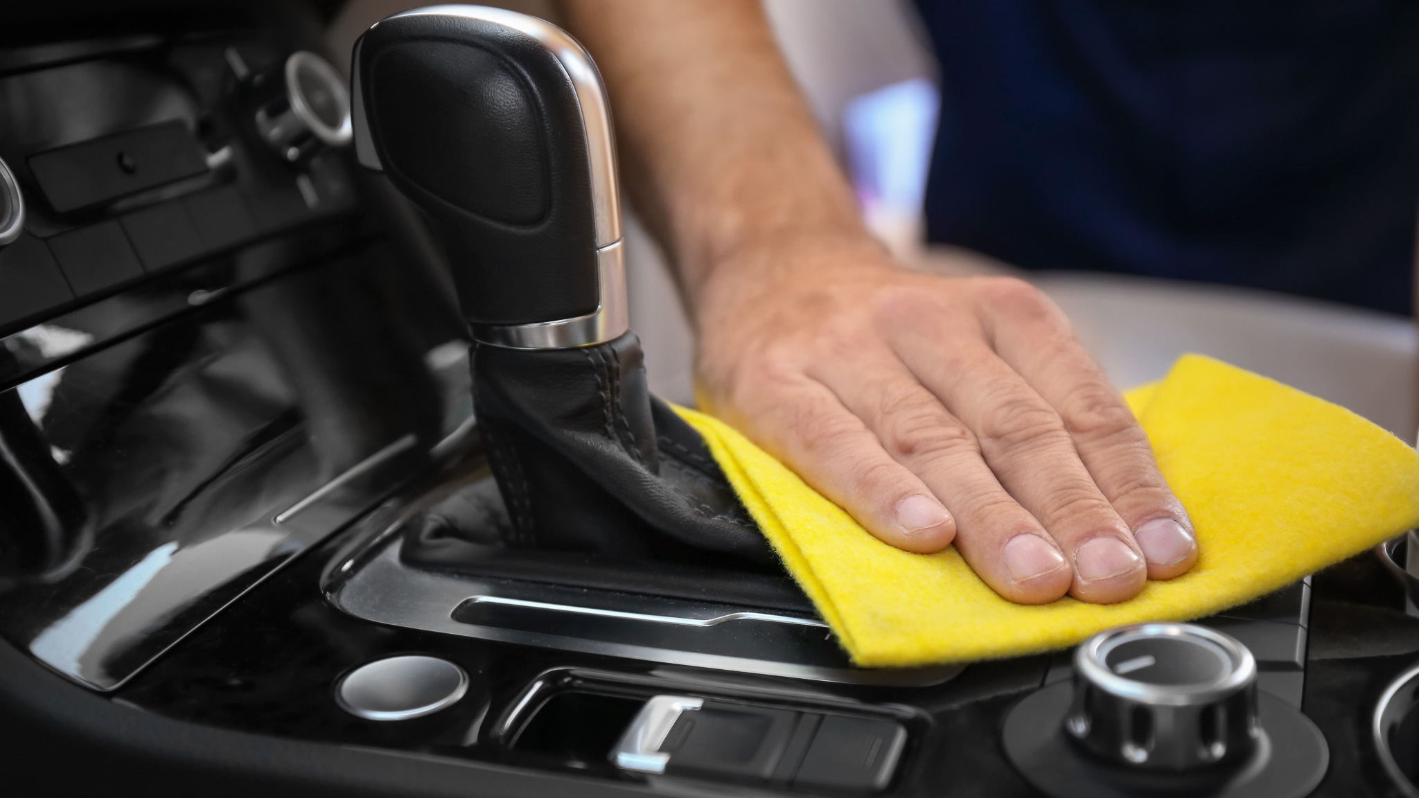 Man cleaning car gear lever with rag, closeup